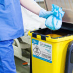 A person wearing a hospital costume is putting waste in a disposal bin.