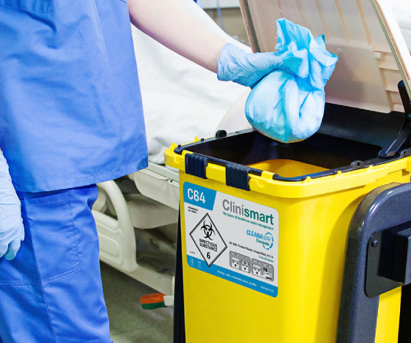 A person wearing a hospital costume is putting waste in a disposal bin.