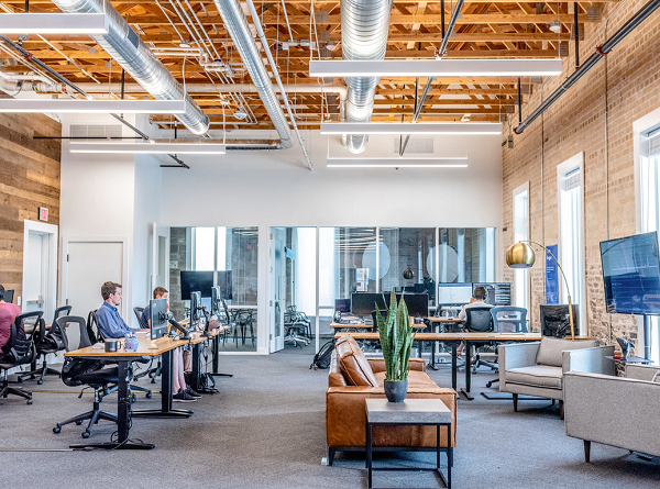 A office environment where employees are working busily in front of the computer system, chairs, flowerpots table lamps can be seen.