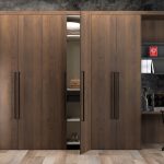 Modern wooden wardrobe with a built-in study desk, open shelves, and a stylish office chair in a well-designed room.